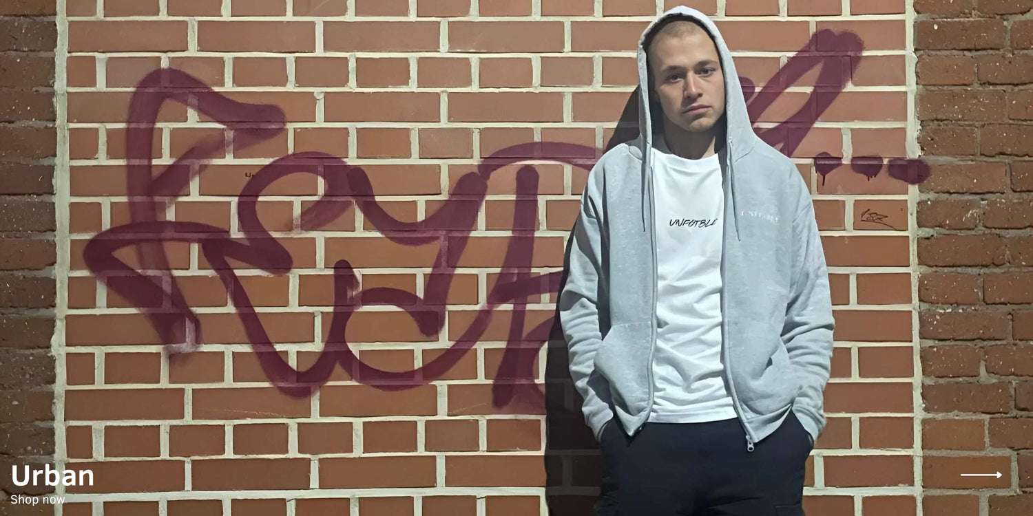 Modell steht in unfgtble Urban Kollektion Streetwear vor Graffit-Ziegelwand