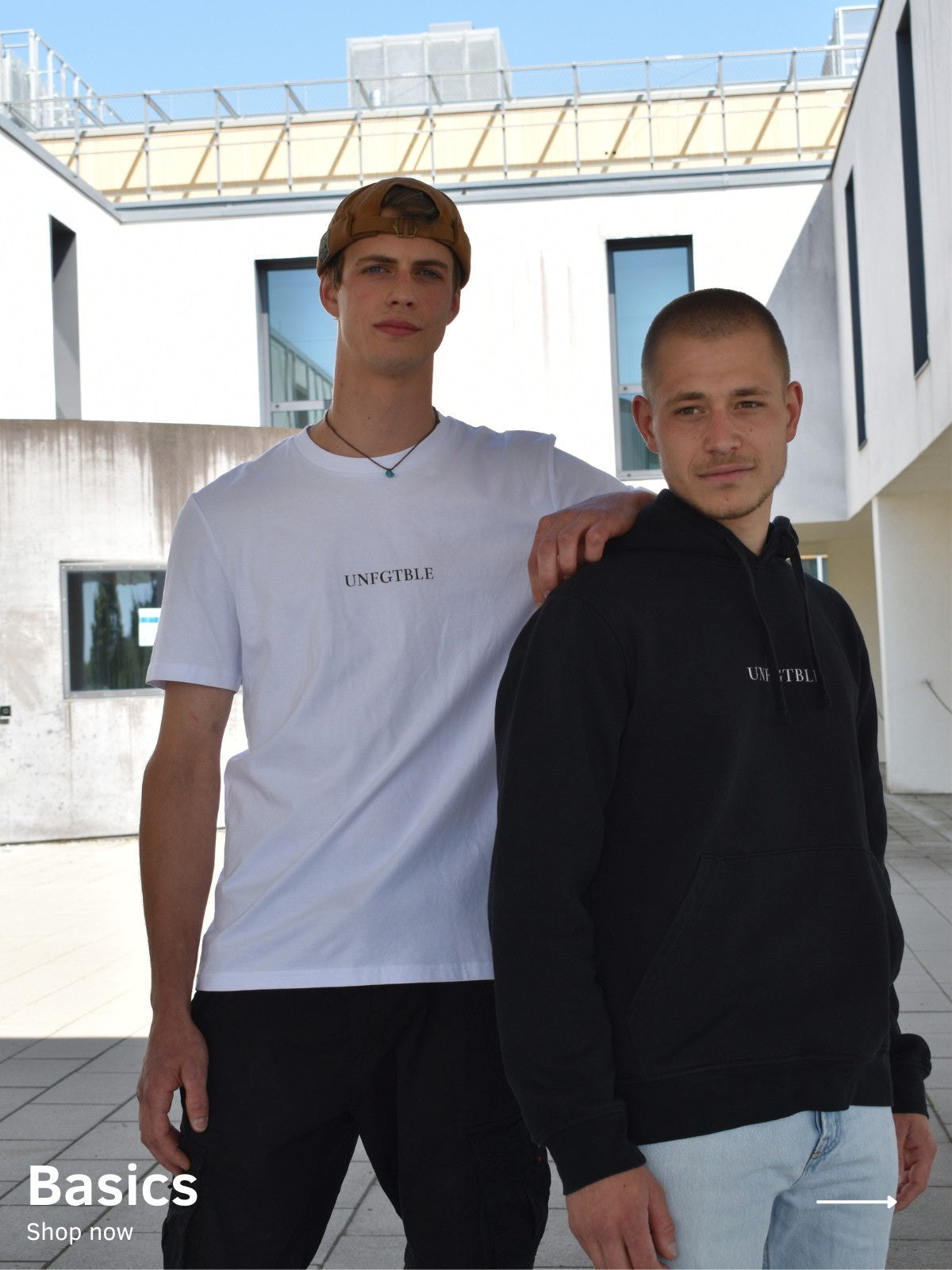 Zwei Männer, der linke trägt ein weißes Oversized T-Shirt mit schwarzem unfgtble Schriftzug, der rechte trägt einen schwarzen Hoodie mit weißem unfgtble Schriftzug
