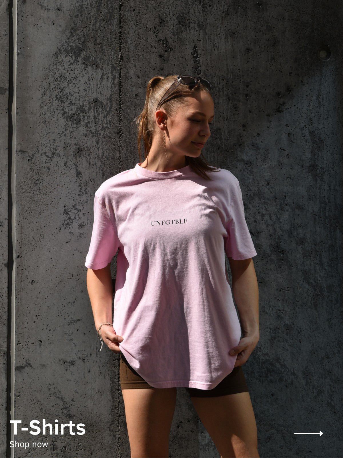 Eine Frau trägt ein pinkes Oversized T-Shirt mit schwarzem unfgtble Schriftzug